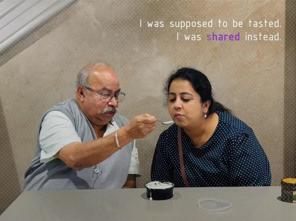 A father feeding his grown daughter a spoonful of dessert