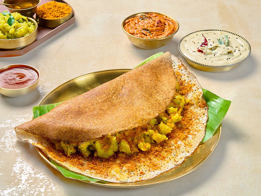 Ghee podi masala dosa folded over its potato masala, chutneys alongside