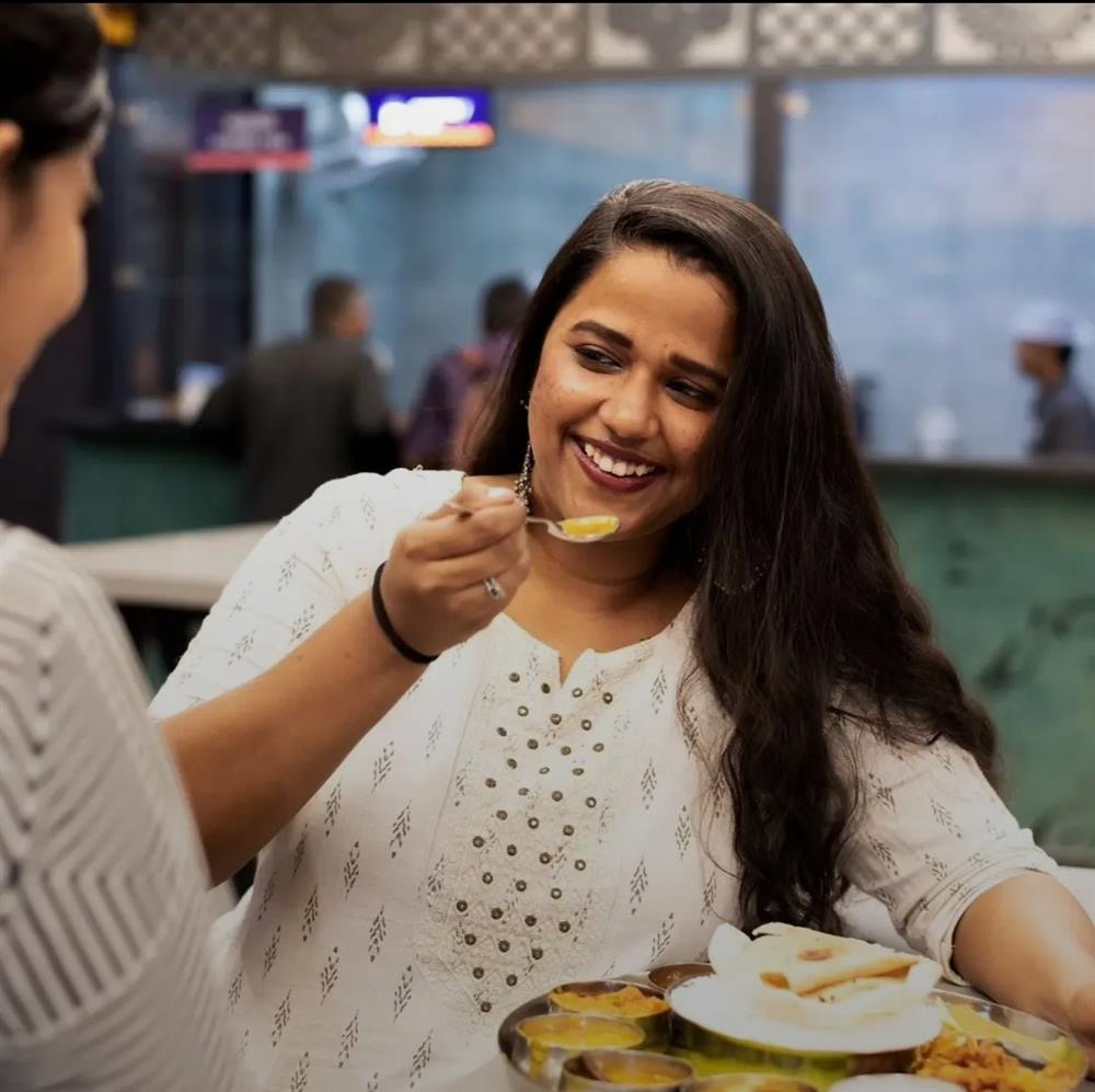 A woman mid-laugh over a thali